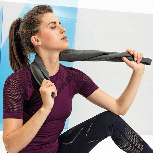 Female wearing a burgundy t shirt and black legging with a grey gym towel around her neck