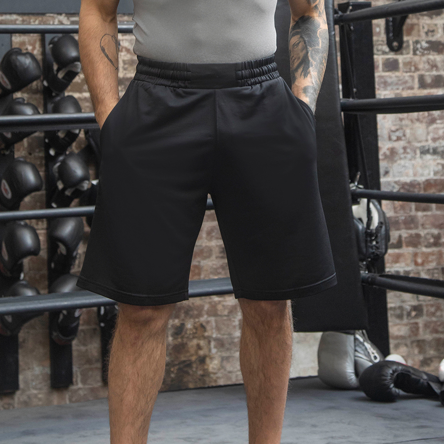 Male wearing black shorts and grey t shirt standing in boxing ring